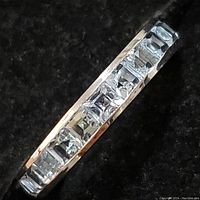 Top-down view showing channel-set princess-cut light blue topaz stones along the band