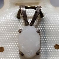 Close-up front view of the sterling silver pendant showing the white opal stone and prong setting.