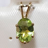 Close-up front view of the oval faceted peridot gemstone pendant set in sterling silver, showing prong setting and bail.