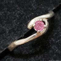 Close-up photo of the sterling silver ring showing the small round ruby held by prongs on a curved band.