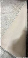 Close up of the white soft fur rug showing fabric backing and pile texture