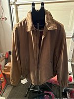 Tan Weatherproof men's jacket displayed on a mannequin, showing front and pocket details.