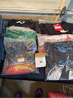 Photo showing 7 packaged new superhero T-shirts featuring Marvel and DC designs including Superman