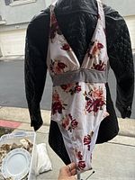 Floral one-piece swimsuit with white base and red, pink flowers, black and white striped band under bust shown on mannequin
