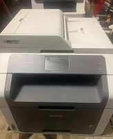 Front view of Brother MFC-9130CW printer showing touchscreen and paper input trays