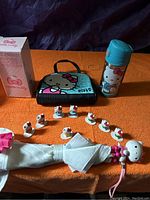 Photo showing all items in the Hello Kitty lot including thermos, miniature figurines, umbrella, purse, and measuring cup.