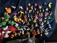 Top-down wide view of numerous colorful animal figurines and play animals arranged on a surface