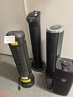 Four black tower-style air purifiers standing together showing fronts and control tops, different brands visible including Ionic Pro Turbo and KazHolmes Aero Cleaner.