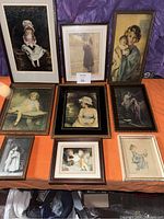 Nine framed antique Victorian pictures arranged on an orange cloth surface showing various portraits of children and women in vintage attire.