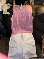 Pink and white sleeveless knit sweater tunic with visible price tag and white shorts underneath.