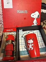 Peanuts branded box with thermos, mug, and two Snoopy hand towels inside.