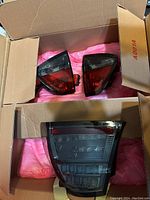Two LED tail light assemblies packaged in a cardboard box with pink cushioning.
