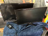 Photo of Vizio TV and Acer monitor side by side on a soft blue cloth, power adapter cable visible.