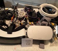 Two Oculus VR headsets placed with audio cables on a table with MaxSold label visible