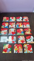 Photo showing full view of 18 vintage Valentine cards laid out, showcasing cartoon characters and heart-shaped messages.