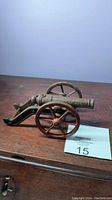 Front angle view of the cast iron miniature signal cannon showing the wheels, barrel, and carriage detail.