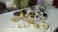 Full lot showing assorted candle holders and decorative metal sun and moon figures on table.