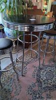 Full view of retro round bar table with chrome legs and matching stools.