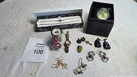 Mixed lot including wristwatches, anklet in display box, earrings, necklace segments and trinkets arranged on a white surface