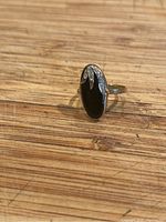 Front view of the ring showing black onyx centerpiece with diamond accented setting in gold.