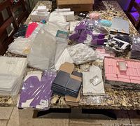 Overview of various gift bags and boxes spread on a table including white, purple, black bags and a pink organizer box.