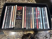 Photo shows a close-up of the collection of music CDs in their jewel cases stored vertically inside a black leather file box. Visible are titles such as Billy Joel's The Stranger, a 3-CD set for The Rat Pack, and others.