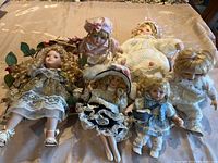 All six porcelain dolls arranged on a surface showing various sizes and styles with one doll playing music