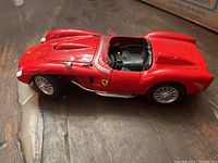 Side angle of red Burago die cast Ferrari Testarossa 1957 model showing detailed body and interior.