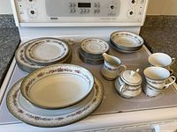 Photo showing entire Noritake Roselane china set on stove top, including plates, bowls, cups, sugar and creamer, and platters
