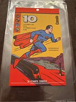 Front view of the Superman stamp package showing Superman running on the card with bright red and yellow colors and train and lighthouse graphics.