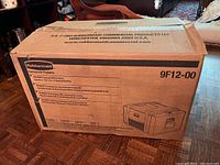 Box packaging showing Rubbermaid Commercial Products branding and model 9F12-00 printed on box with product specifications including compatibility with 3 full size deep pans of size 2 1/2 or 2 4 inch depths.