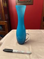 Front view of the turquoise Empoli bud vase showing the shape, color, and clear handle. Marker pen included for scale.