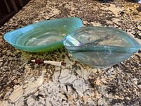 Two vintage green glass swirl bowls placed on a granite countertop with a pen for scale.