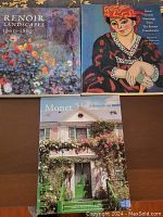 Top view of three coffee table art books - 'Renoir Landscapes 1865-1883', 'Great French Paintings from The Barnes Foundation', 'Monet: A Visit to Giverny' arranged on a table.