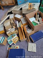 Wide view of many boxes and stacks of art supplies featuring palette pals, X-ACTO blades, markers, and other materials.