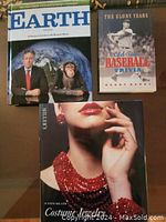Photo of the three assorted coffee table books from the seller's lot: Earth, Costume Jewelry, Baseball Trivia.