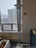 Full view of the tall and slender floor lamp placed near window, showing vertical striped panel and circular top diffuser.