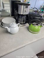 Overview showing coffee maker, kettle, teapot, bowl and toaster on counter.