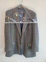 Full length image of the blazer hanging with garment bag showing the front details.