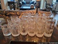 Two short water glasses and two tall highball glasses in front, eight additional highball glasses behind on table
