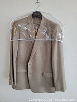 Front view of beige Ralph Lauren men's blazer hanging on a plastic hanger inside a garment cover.