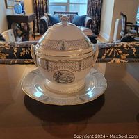 Closed soup tureen with lid and underplate displayed on table