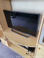 Sony 32-inch television on a wooden TV stand, showing the front and screen angles.