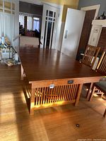 Side view of oak dining table showing vertical slatted panel at end, drawer handle, and overall Craftsman style design.