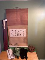 Full lot including Japanese hanging scroll with original purple floral decorative box, three pairs of Gita socks in white, green, and black, two folded kimono sashes, and wooden incense burner on a flat surface.