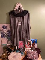 Full view of the lot with grey medium cardigan with pleat, vintage purses, scarves, candles, necklaces, bracelets, calendar, and burgundy poncho sweater visible