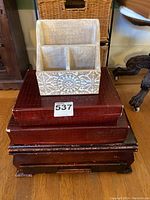 Photo showing silverware chest covered with silver plating and Japanese lacquer boxes stacked beneath, with wooden desk organizer on top.