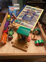 Lot overview showing the book, trains, rail cars, and wooden accessories including road signs and track pieces arranged inside a wooden box.