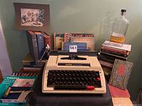 Typewriter with books and additional items arrayed behind, showing overall lot contents