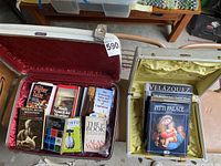 Larger white American Tourister suitcase open showing books inside related to psychology, history and spirituality.